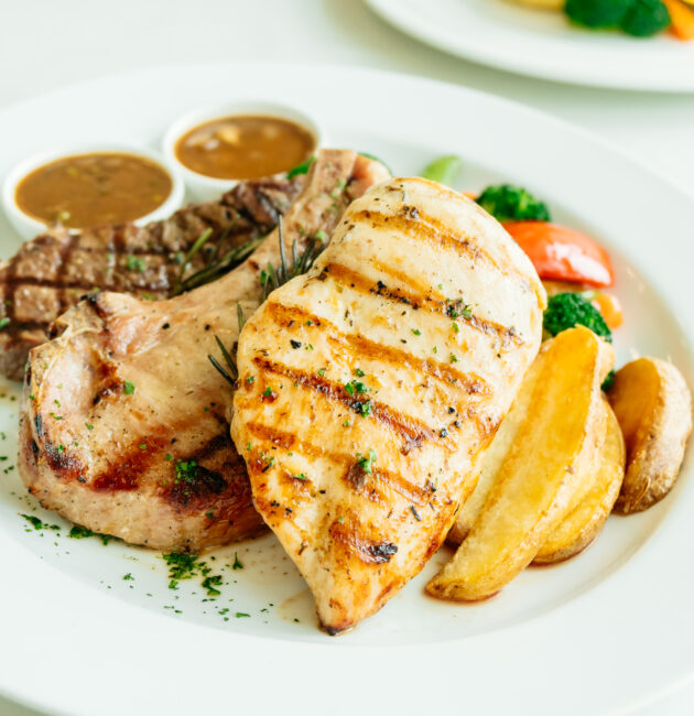 Grilled Chicken breast and Pork chop with beef meat steak and vegetable in white plate